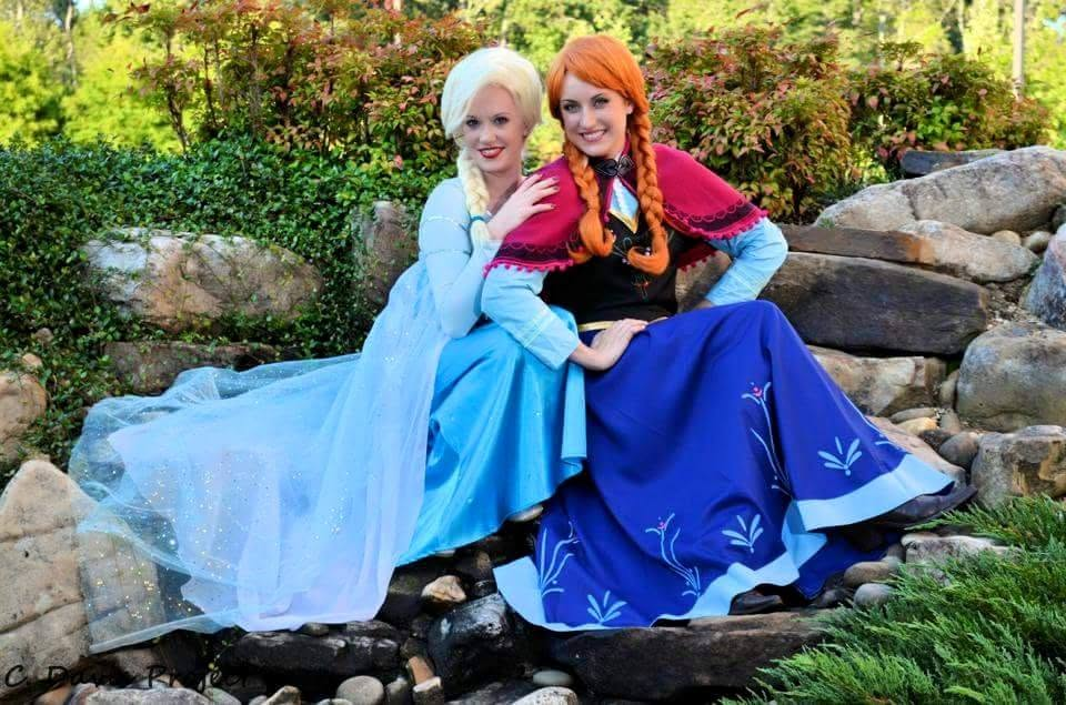 Two performers in coordinating blue and purple winter princess gowns outdoors